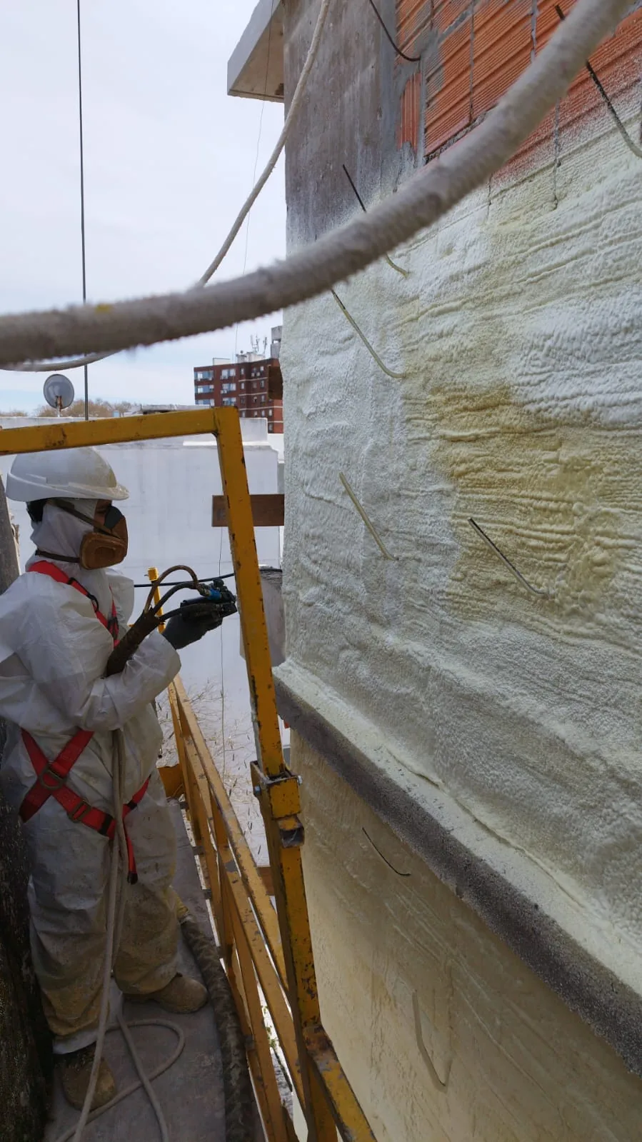 Operario aplicando poliuretano proyectado en una pared exterior